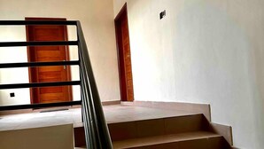 Una escalera con una puerta de madera en la parte superior y un pequeño respiradero en la pared.