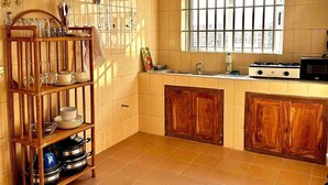 Una cocina con estante de madera, paredes de azulejos, una ventana y una estufa.