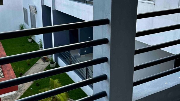 Un edificio moderno con balcón y vista a un patio verde.