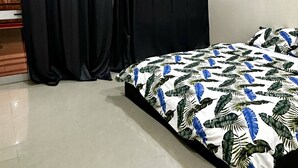 Un dormitorio con cama, cortinas negras y suelo de baldosas.