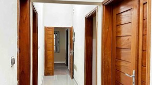 Un pasillo con puertas de madera y suelo de baldosas.