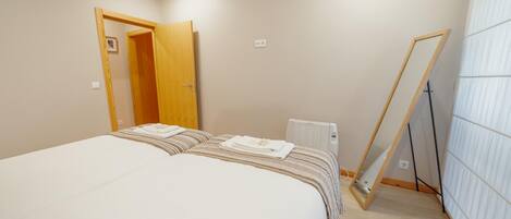 Un dormitorio con una cama, una puerta de madera, un radiador y un espejo apoyado contra la pared.