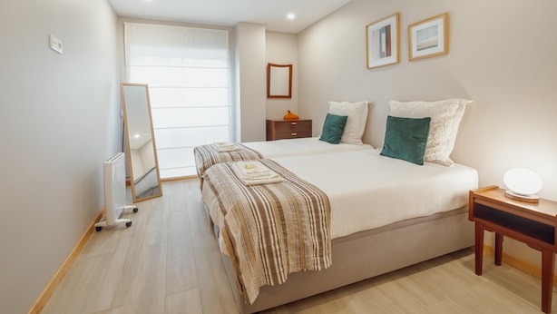 A bedroom with a large bed, bedside tables, a mirror, and framed pictures on the wall. - Good Morning Apartment With Garage by Vacationy (Porto)