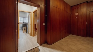 A hallway with wooden doors, a tiled floor, and a visible kitchen area in the background. - Good Morning Apartment With Garage by Vacationy (Porto)