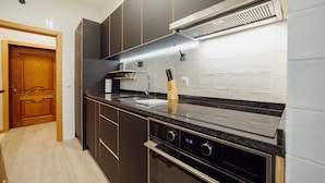 A modern kitchen with dark cabinets, a black countertop, and stainless steel appliances. - Good Morning Apartment With Garage by Vacationy (Porto)