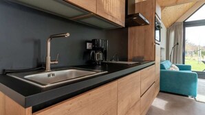 Una cocina moderna con armarios de madera, encimera negra y pileta de acero inoxidable integrada.
