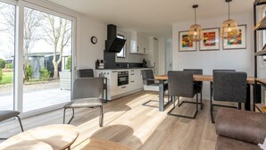 Eine moderne Küche mit Essbereich, großen Fenstern und Blick ins Freie.