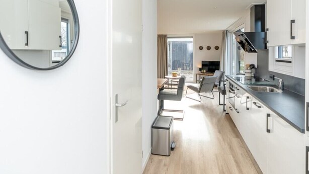 Eine moderne Küche mit weißen Schränken, einer schwarzen Arbeitsplatte und einem großen Fenster.