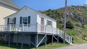 A two-story house with a balcony, a red door, and a staircase leading to the upper floor.