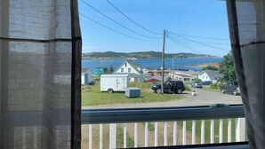 A view from a window with a view of a small community, including houses, a trailer, and a body of water.