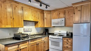 A kitchen with wooden cabinets, a white stove, a microwave, and a refrigerator. - Cozy 2-Bedroom Upstairs Apartment in  Paradise (Paradise)