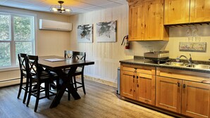 A kitchen with wooden cabinets, a granite countertop, and a dining area with a table and chairs. - Cozy 2-Bedroom Upstairs Apartment in  Paradise (Paradise)