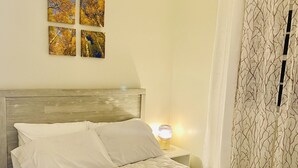 A neatly made bed with white bedding, a headboard, and a bedside lamp.