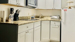 A kitchen with white cabinets, a microwave, a sink, and a refrigerator.