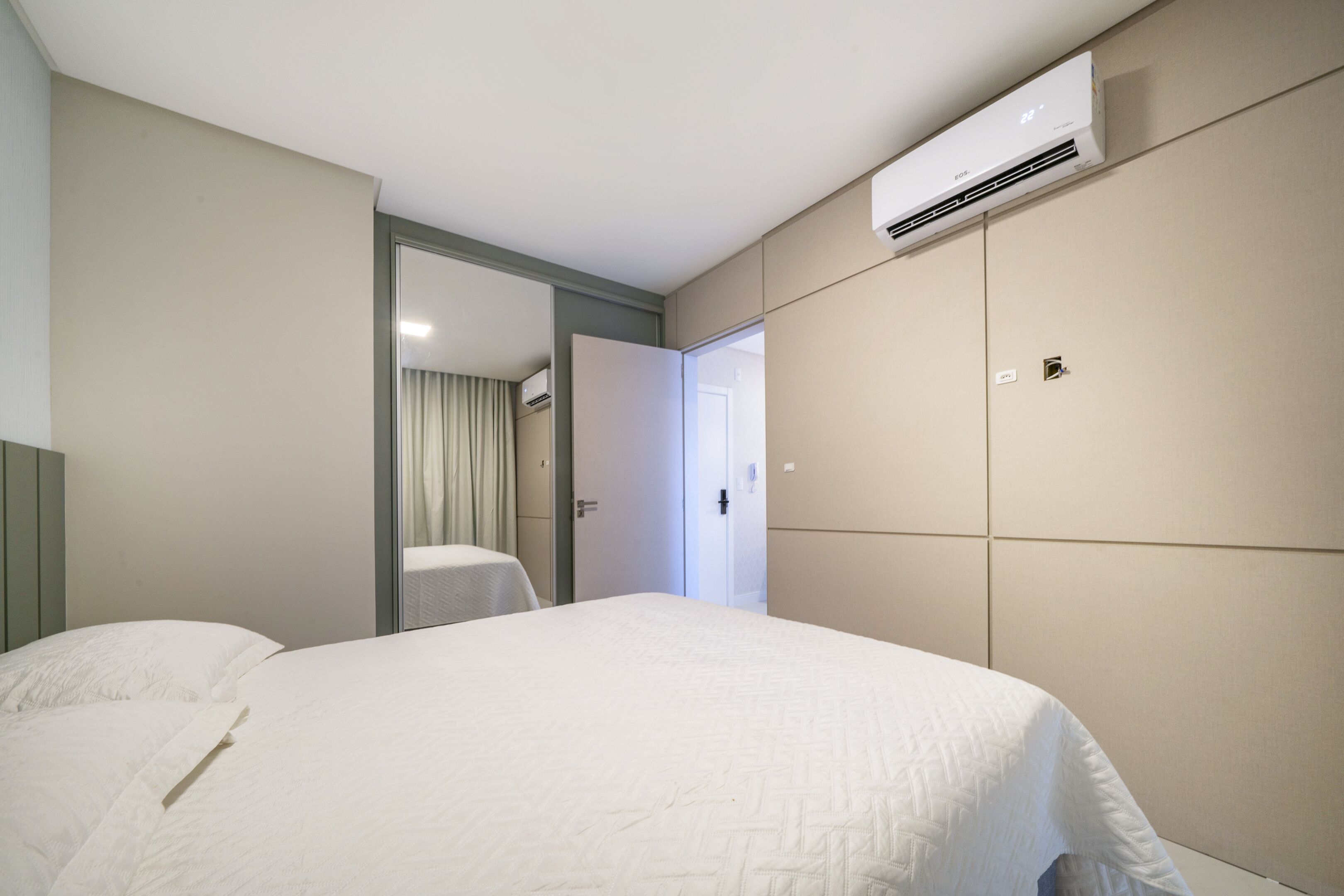 Ein Hotelzimmer mit Bett, Klimaanlage, einer Tür zu einem anderen Raum und einem Vorhang.