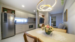 Una cucina moderna con elettrodomestici integrati, un'area pranzo con tavolo imbandito per due e una zona living con divano e televisione.