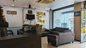 A reception area with a marble wall, a television, and a Buddha statue. - RBS Residency (Tiruchirappalli)