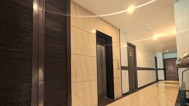 A hallway with a tiled floor, a closed elevator, and a door with a sign. - RBS Residency (Tiruchirappalli)