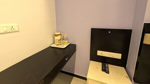A hotel room with a black desk, a small table with a tray of toiletries, and a black headboard with a mirror. - RBS Residency (Tiruchirappalli)