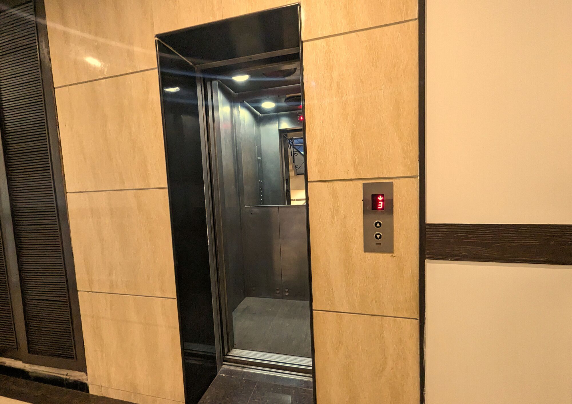 Un ascensor con interior metálico, una pantalla digital y un panel de control con botones.