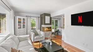 A modern living room with a fireplace, white furniture, and a mounted TV. - Enjoy a stylish experience at this fresh and clean  lower apartment!  This place is newly renovated and perfect for a stay in the Metro Detroit. It's located near the Detroit Zoo right by major highways. This home is a duplex building and includes 2 (Oak Park)