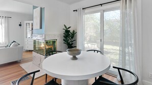 A modern dining area with a round table, chairs, a fireplace, and a large window with curtains. - Enjoy a stylish experience at this fresh and clean  lower apartment!  This place is newly renovated and perfect for a stay in the Metro Detroit. It's located near the Detroit Zoo right by major highways. This home is a duplex building and includes 2 (Oak Park)