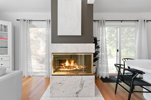 A modern living room with a fireplace, white furniture, and large windows. - Enjoy a stylish experience at this fresh and clean  lower apartment!  This place is newly renovated and perfect for a stay in the Metro Detroit. It's located near the Detroit Zoo right by major highways. This home is a duplex building and includes 2 (Oak Park)