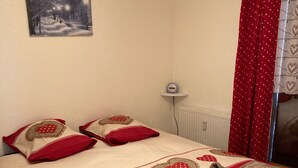 Une chambre à coucher avec un lit, des oreillers, une couverture, une table de chevet, une horloge murale et un tableau.