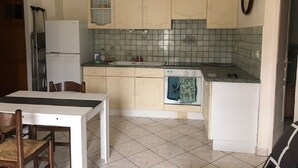 Une cuisine de taille réduite comprenant une table à manger, des placards, un réfrigérateur et une cuisinière.
