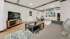 A modern living room with a wooden entertainment unit, a large flat-screen TV, a coffee table, and a sofa.