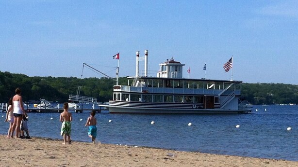 A riverboat docked at a sandy beach with a forested background.