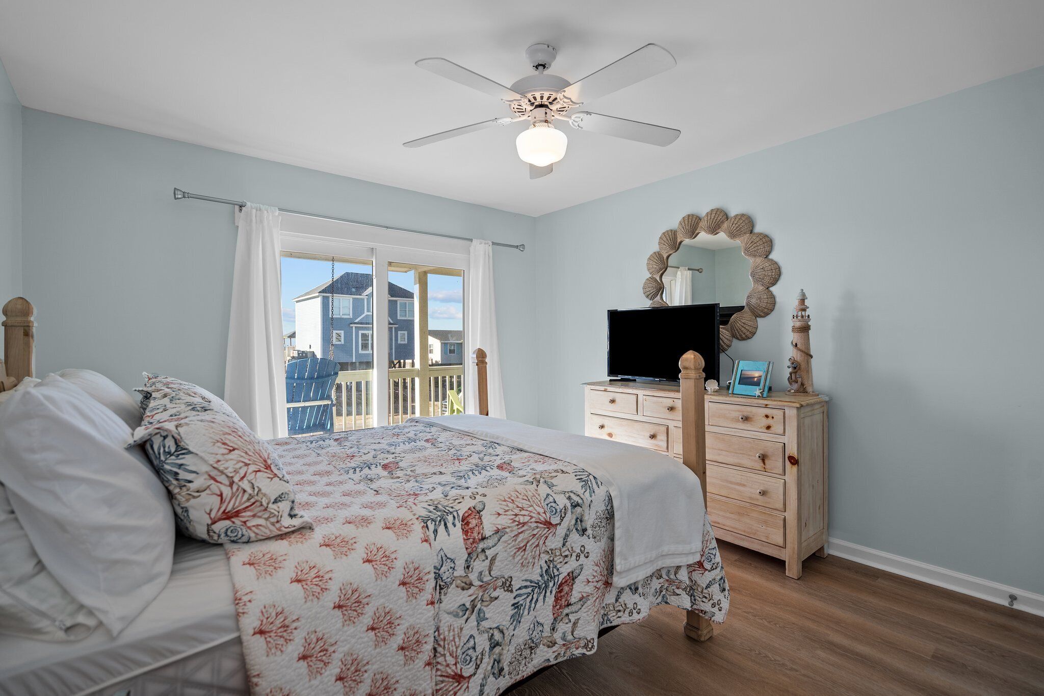 Une chambre à coucher comprenant un lit, une commode, un téléviseur et un ventilateur de plafond.