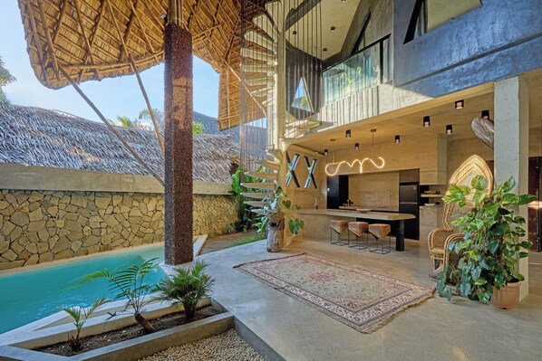 A modern outdoor living area with a pool, stone walls, and a dining setup.