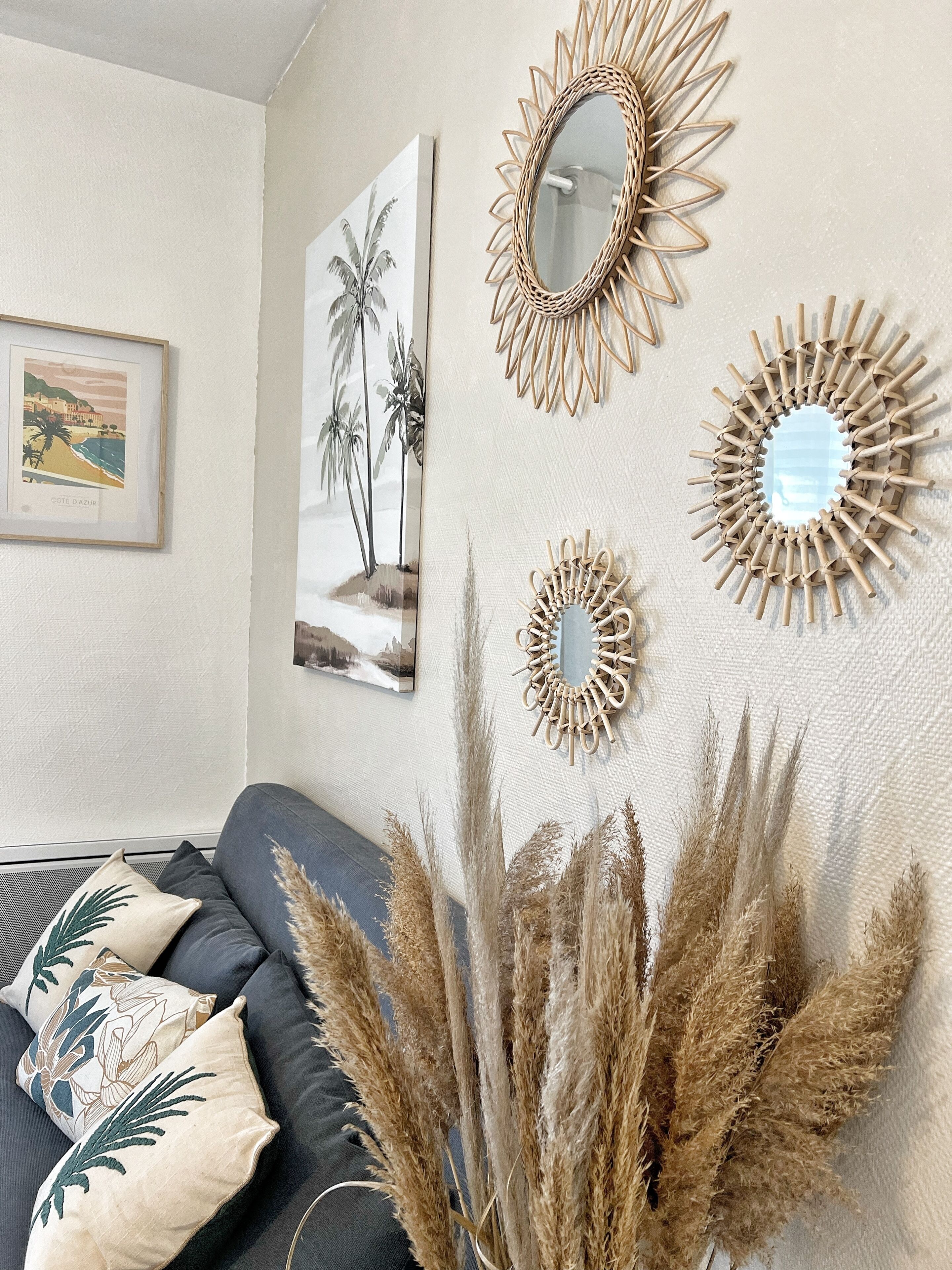 A room with a sofa, decorative mirrors, and wall art.