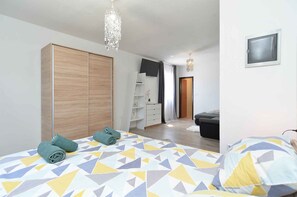 Une chambre à coucher moderne avec un lit, une armoire, un téléviseur et un lustre.