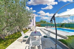 Une terrasse extérieure avec une piscine, une table et des chaises, et une pergola.