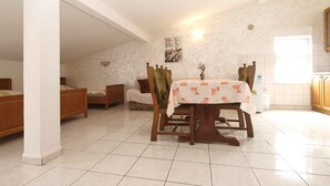 A spacious room with a dining table, two chairs, a sofa, and a bed.
