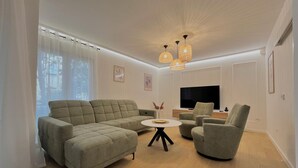 Una sala moderna con un sofá modular, una mesa de centro redonda y un televisor de pantalla plana.