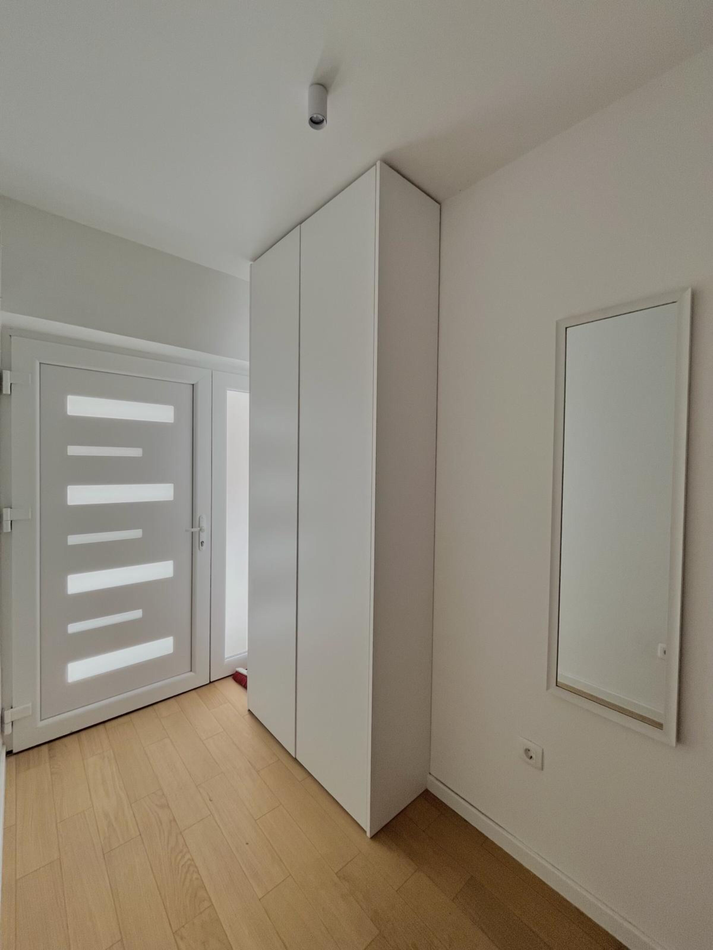 Una habitación con puerta corredera, armario y espejo en la pared.