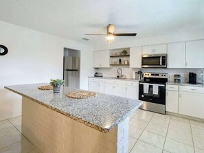 A modern kitchen with granite countertops, stainless steel appliances, and white cabinetry.