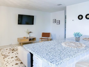 A modern living room with a large TV, a wooden cabinet, a chair, and a decorative rug. - Fillmore Unit 14 (Cape Canaveral)