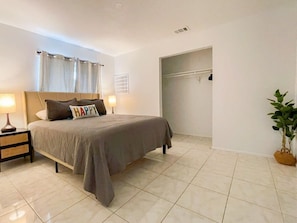 A bedroom with a bed, nightstands, a potted plant, and a closet. - Fillmore Unit 14 (Cape Canaveral)