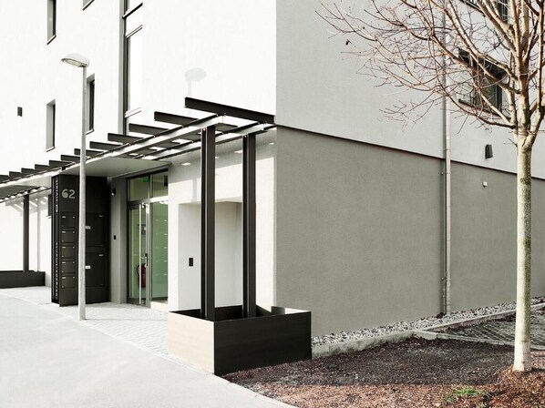 A modern building with a glass entrance, a black door, and a staircase leading to an upper level.