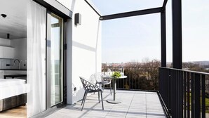 A modern apartment with a balcony, a dining area with a table and chairs, and a view of the cityscape.