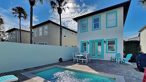 Une maison moderne à deux étages, dotée d ’une piscine, d’un espace salon extérieur et de palmiers.