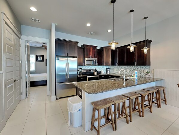 A modern kitchen with dark wood cabinets, stainless steel appliances, and a central island with bar stools.