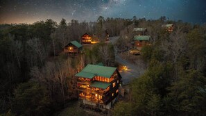 Un complexe hôtelier composé de plusieurs bâtiments entourés de forêt, dont le bâtiment principal se distingue par sa structure à deux étages, son toit végétalisé et ses nombreuses fenêtres.
