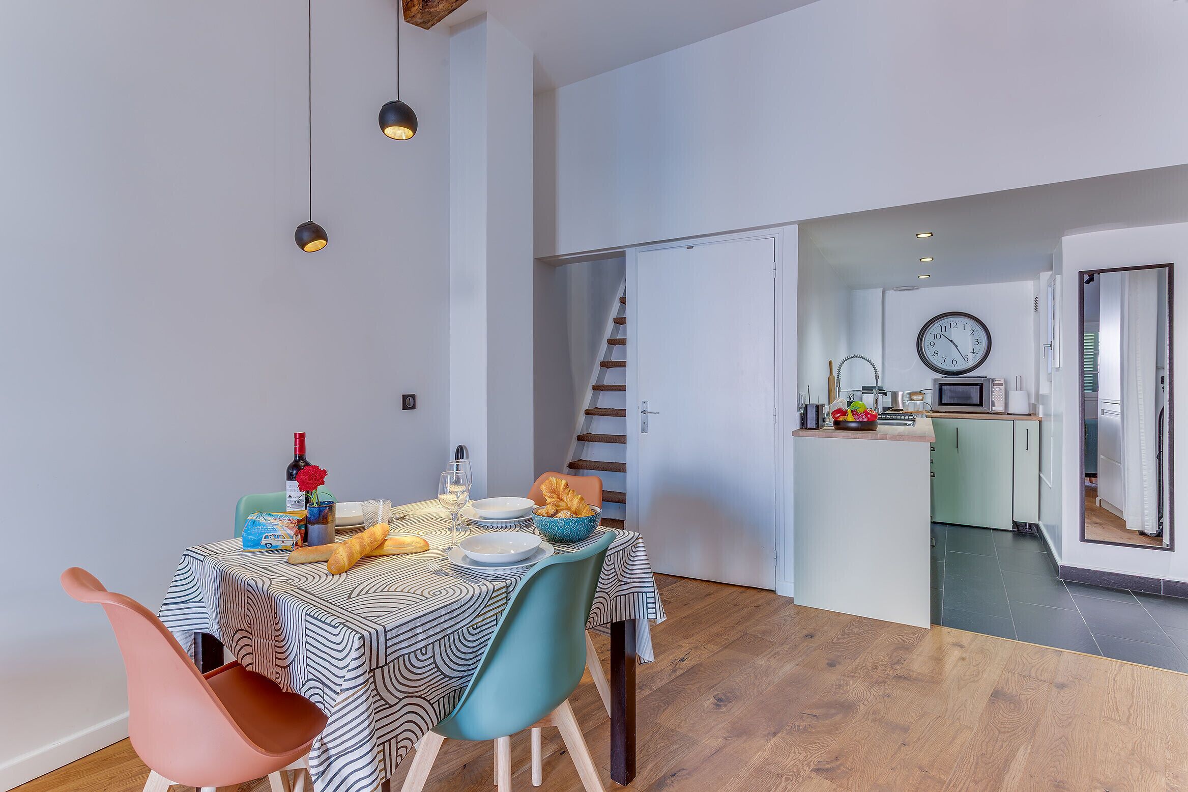A modern kitchen with a microwave, toaster, and clock on the wall.