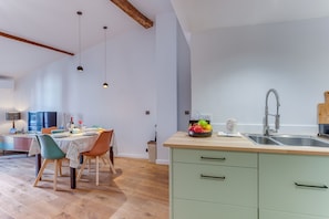 Una cocina moderna con encimera de madera, un lavabo y una zona de comedor con mesa y sillas.