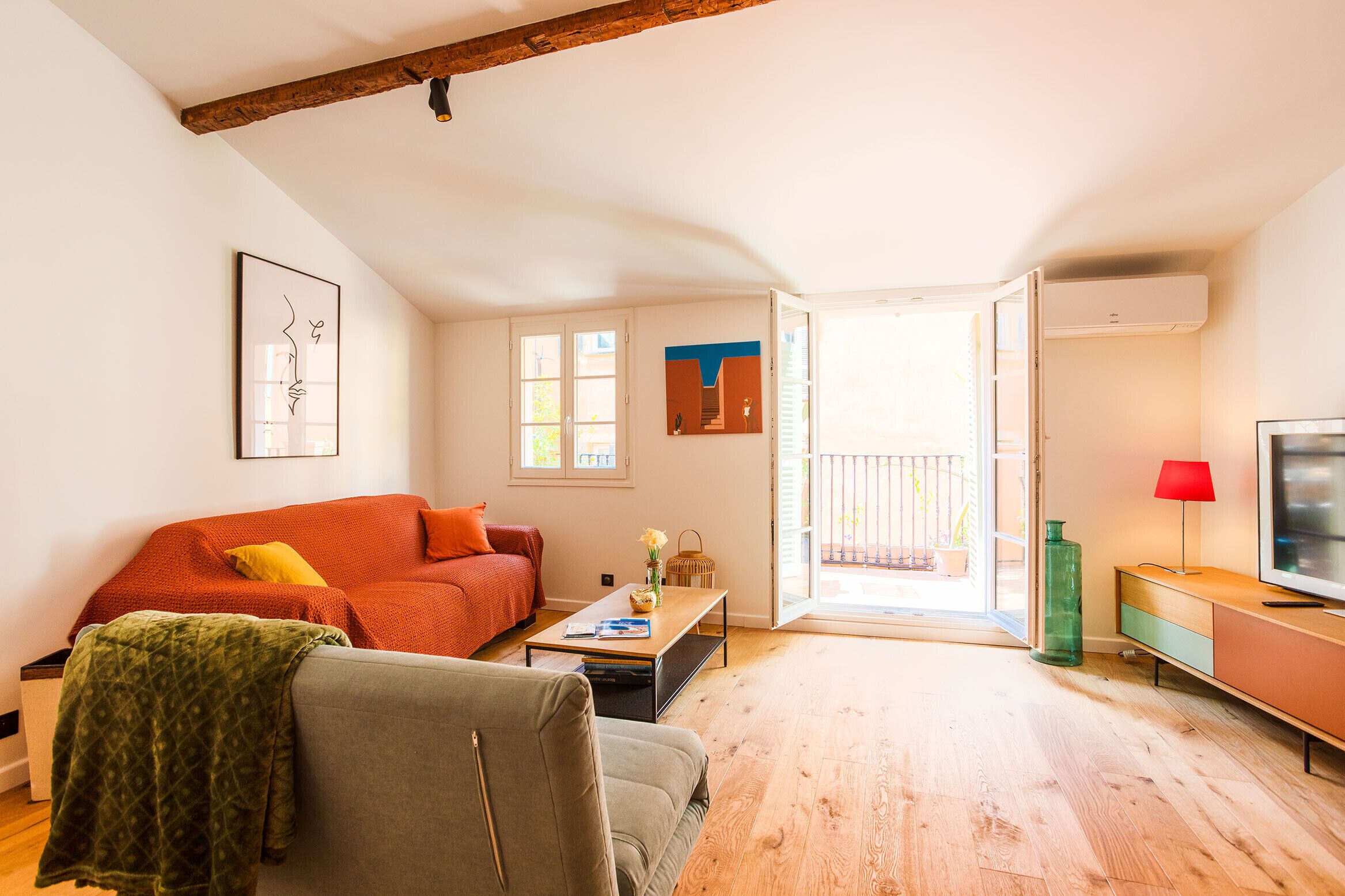 A spacious living room with a wooden floor, a sofa, a coffee table, and a TV on a stand.